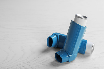 Asthma inhalers and space for text on white wooden background