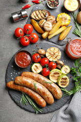 Delicious sausages and vegetables served for barbecue party on gray background, top view