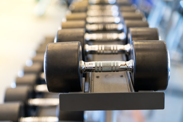 Naklejka premium Closeup rows of metal dumbbells on rack in the gym