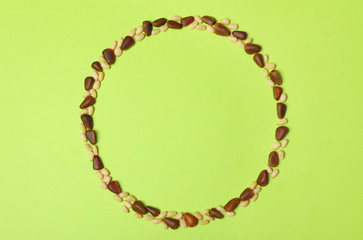Frame made with pine nuts and space for text on color background, top view