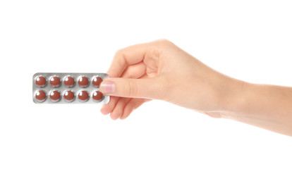 Woman holding pills in blister pack on white background, closeup