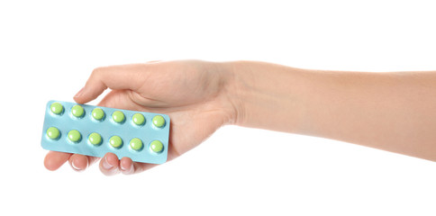 Woman holding pills in blister pack on white background, closeup