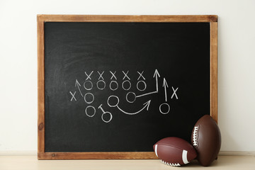Rugby balls near chalkboard with football game scheme on table © New Africa