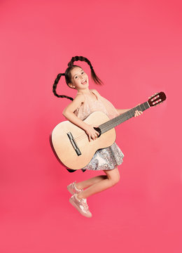 Cute little girl playing guitar on color background