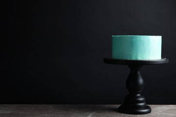 Fresh delicious birthday cake on stand against black background. Space for text