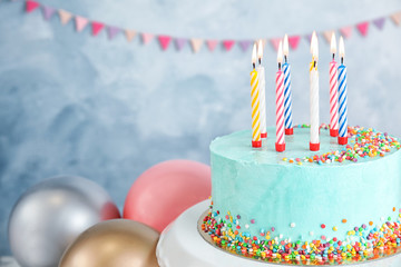 Fresh delicious birthday cake with candles near balloons on color background. Space for text