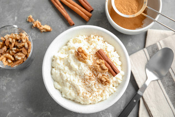 Creamy rice pudding with cinnamon and walnuts in bowl served on grey table, top view