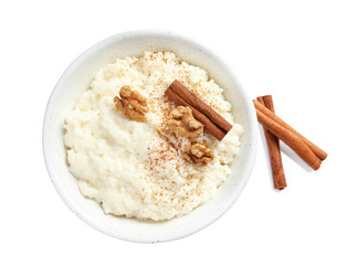 Creamy rice pudding with cinnamon and walnuts in bowl on white background, top view