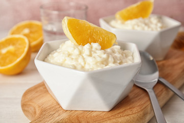 Creamy rice pudding with orange served on wooden table