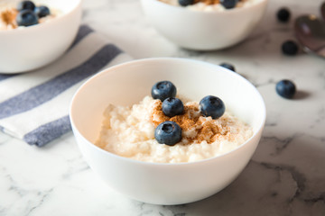 Creamy rice pudding with cinnamon and blueberries in bowl on marble table