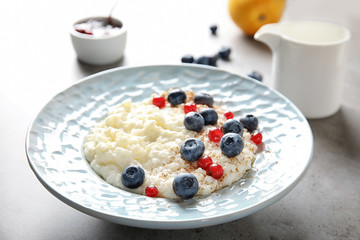 Creamy rice pudding with red currant and blueberries in bowl served on table