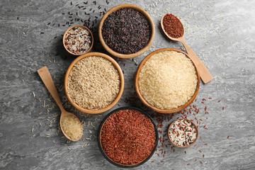 Flat lay composition with brown and other types of rice on grunge background