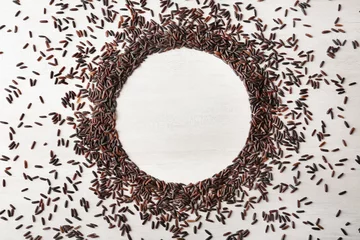 Poster Round frame made with black rice on white wooden background, top view. Space for text © New Africa