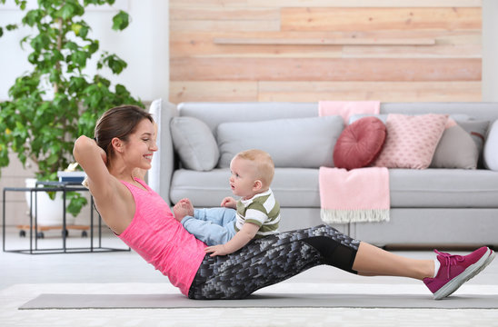 Young sportive woman doing exercise with her son at home. Fitness training