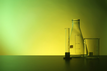 Empty chemistry laboratory glassware on table against color background