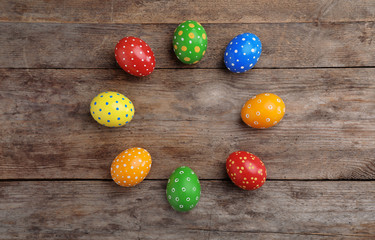 Decorated Easter eggs and space for text on wooden background, top view