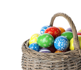 Decorated Easter eggs in wicker basket on white background