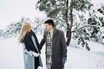 Happy loving couple walking in winter park enjoying snow