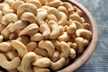 Tasty cashew nuts in wooden bowl on table, closeup