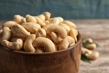 Tasty cashew nuts in wooden bowl on table, closeup