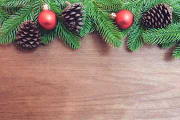 Christmas background. Fir tree branches, red Christmas ball and pine cones with decoration on a wooden board. with copy space for text.