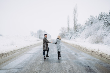 A couple running on the empty road in the winter forest