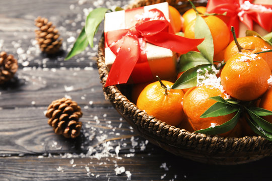 Bowl with ripe tangerines, Christmas gift and artificial snow on wooden table, closeup. Space for text
