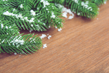 Naklejka premium Christmas background. Fir tree branches and with snow decoration on a wooden board. with copy space for text.