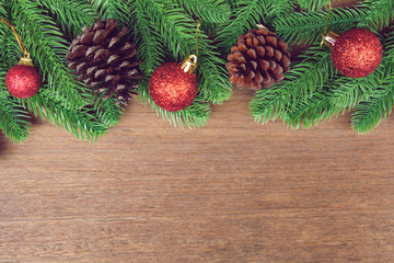 Christmas background. Fir tree branches, red Christmas ball and pine cones with decoration on a wooden board. with copy space for text.