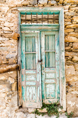 old green and mint wooden door of a stone house on a Greek Island