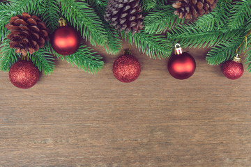 Christmas background. Fir tree branches, red Christmas ball and pine cones with decoration on a wooden board. with copy space for text.