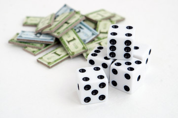 Playing a game about economics; dices, money scattered on white surface. Blurred background. 