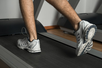 The legs of man running on treadmill in the gym. Health and sport concept. Healthy lifestyles