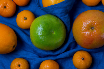 beautiful juicy appetizing fruit citrus orange Mandarin grapefruit sweeties lying on blue fabric background closeup