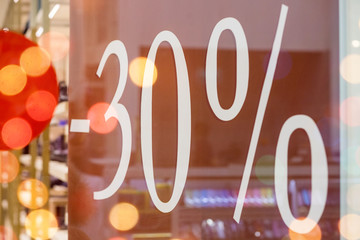 Sale. Shop window with 30 percent discount. Winter sale. Window shop with dressed mannequin, text Sale and 30 percent discount.Seasonal discounts in the store.New Year discounts.The final sale at a