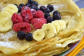 Delicious hot pancakes with fresh fruit on wooden background.