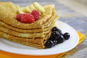 Delicious hot pancakes with fresh fruit on wooden background.
