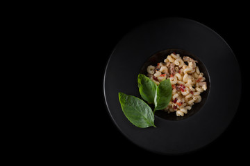 Macaroni with meat and paprika on a black background, view top