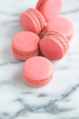 Coral cakes macarons or macaroons on white marble.