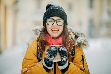 Close up portrait of happy girl in frosty winter city. Flying snowflakes. Smiling to camera, joyful cheerful mood, emotions