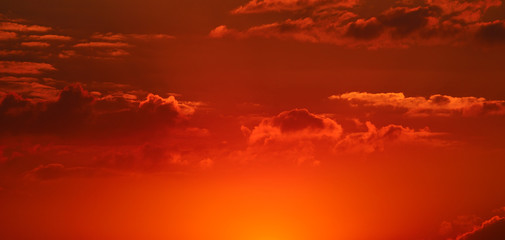 Cloudy sky and bright sun rise over the horizon. Wide photo.
