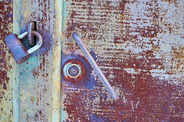 Old metal door painted with gray paint with rust and cracks close-up.
