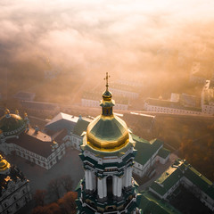 Aerial view of Kiev Pechersk Lavra at dawn and the city covered with thick fog in the background.