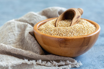 Raw quinoa and a scoop in a wooden bowl.