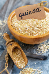 White quinoa in a wooden bowl and scoop.