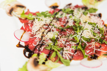 Tasty salad from fish, salad, cheese and mushrooms on white plate in the restauratn