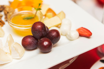 Tasty dessert with grapes, cheese and sauce on white plate in a restaurant