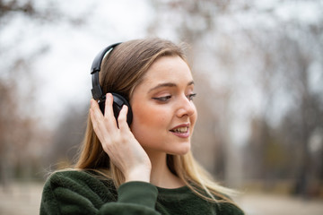 Portrait of smiling female listening to music in headphones in park