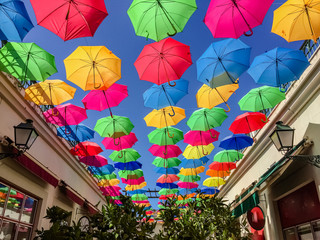 Fototapeta na wymiar Colorful umbrellas on the blue sky on a bright day, bright colors of the summer