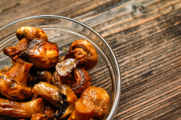 Grilled champignon mushroom in glass bowl on old wooden table